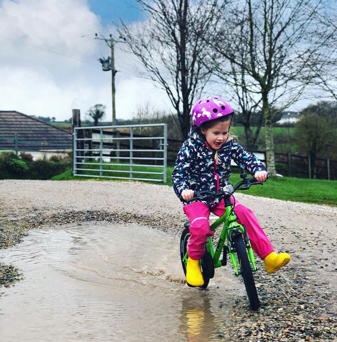 child cycling with only one foot on the pedals and smiling taken by instagram @kids_life_coastal